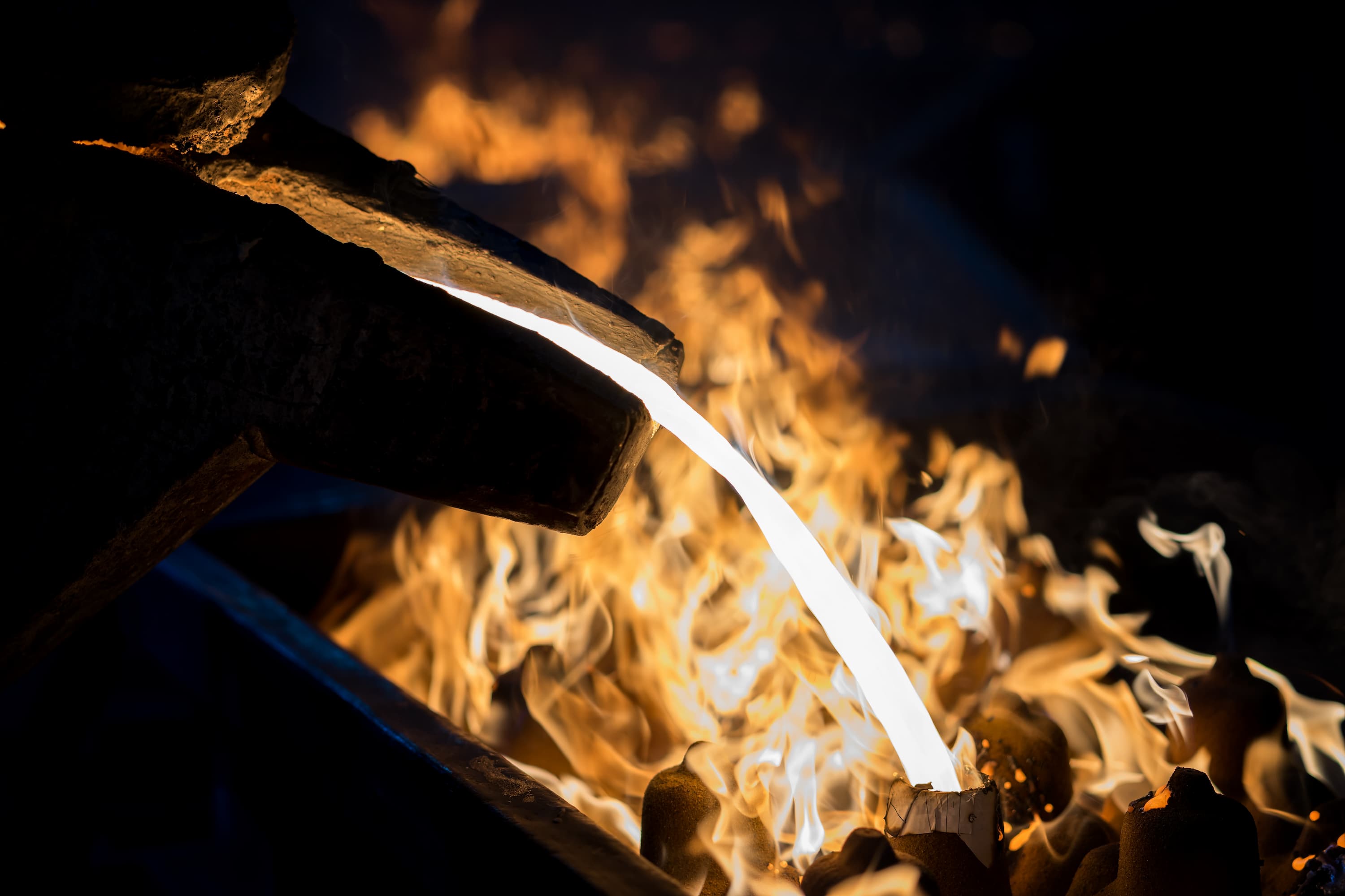 Engineer pouring metal casting parts from ladle in foundry specialized in sand casting simulation.